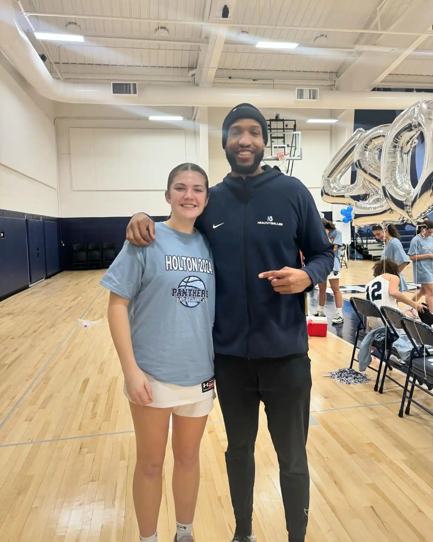 Two people posing in a basketball gym.