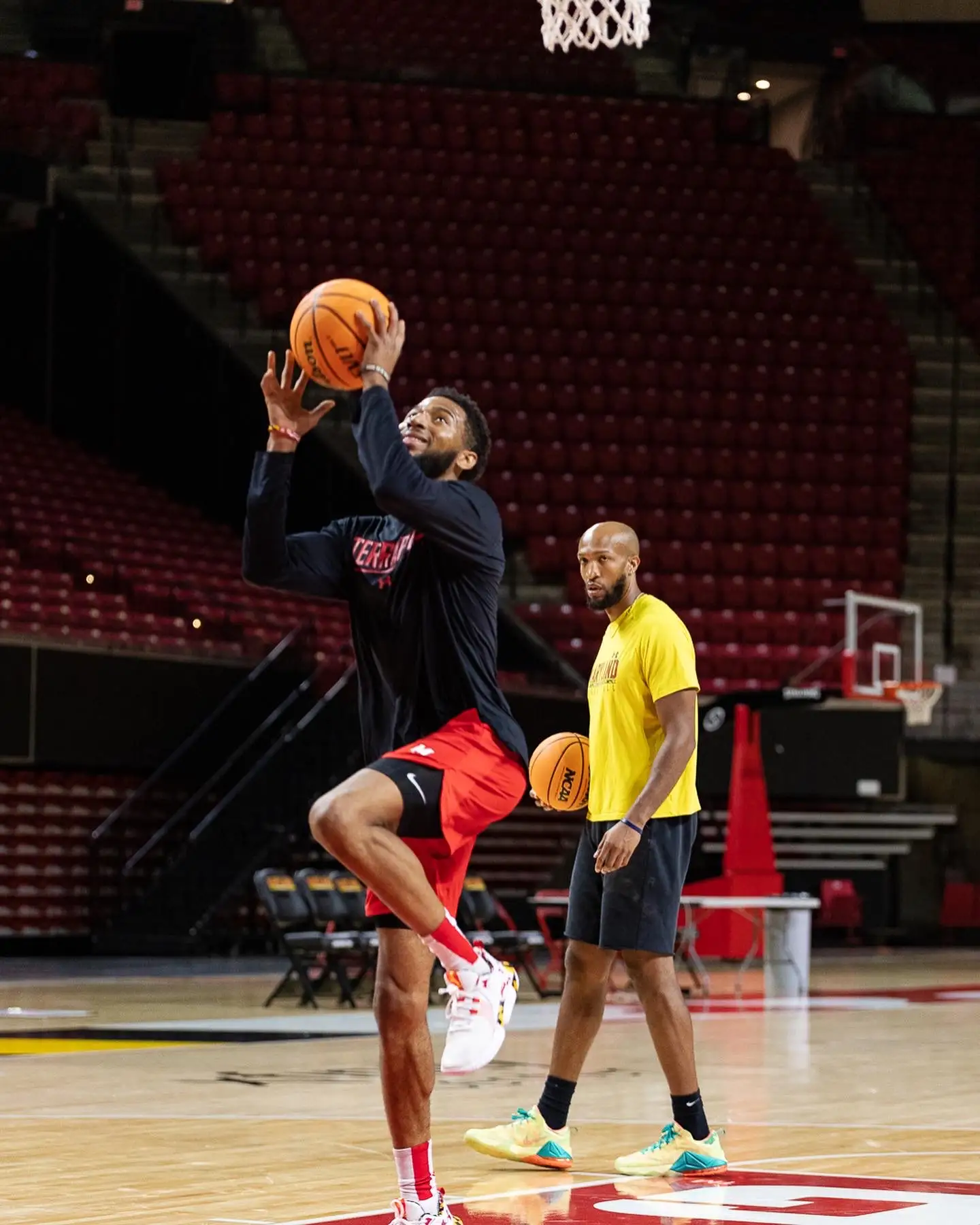 Basketball player practicing a jump shot in gym.