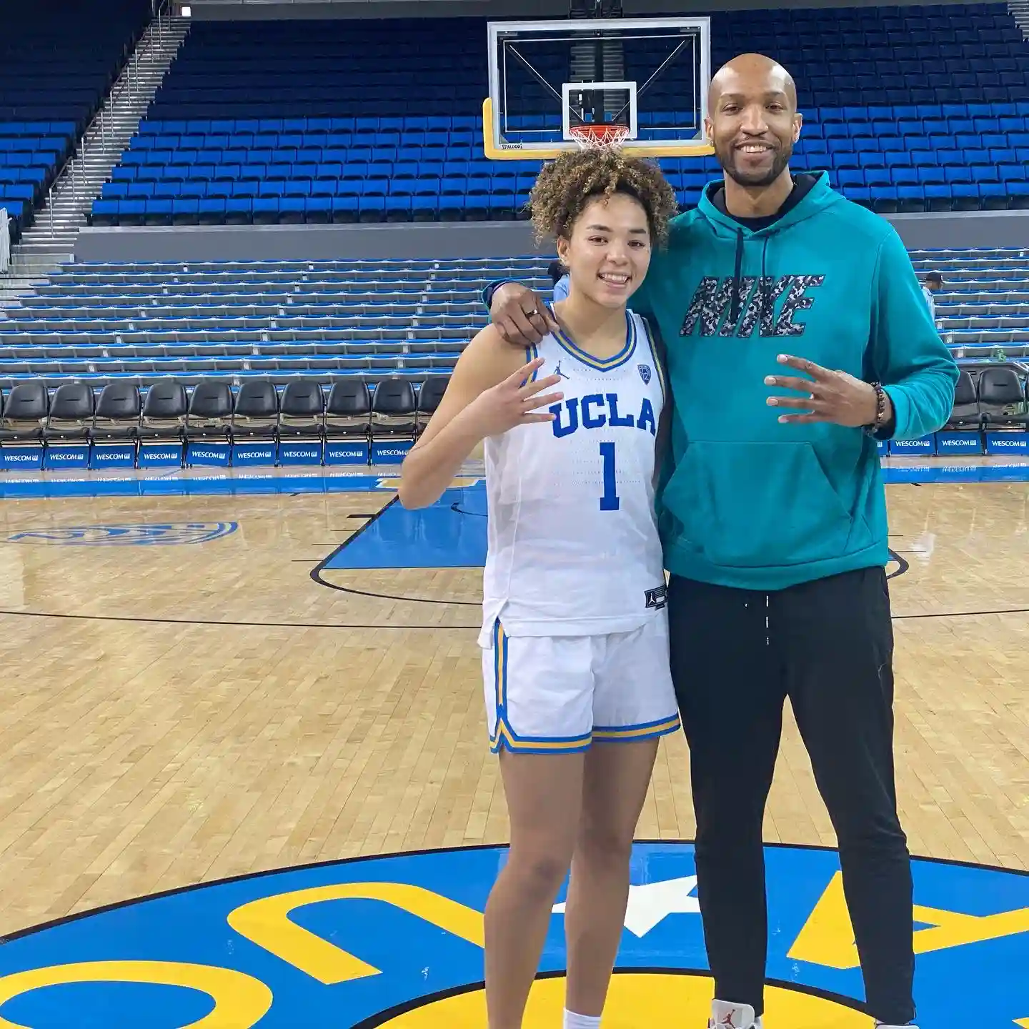 UCLA basketball player poses on court with coach.