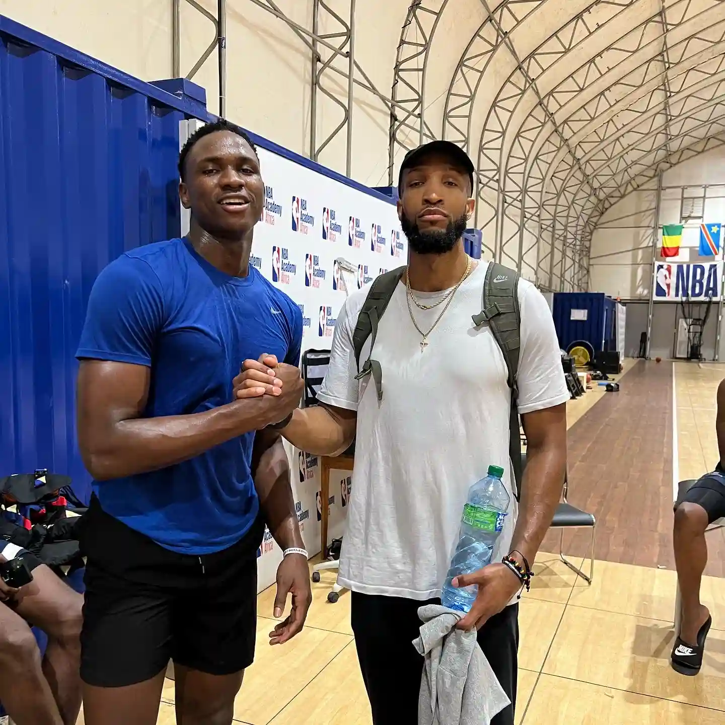 Two men shaking hands in sports facility.