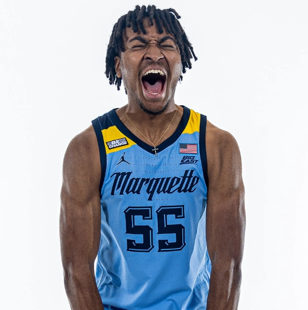 Excited basketball player in Marquette uniform celebrates.