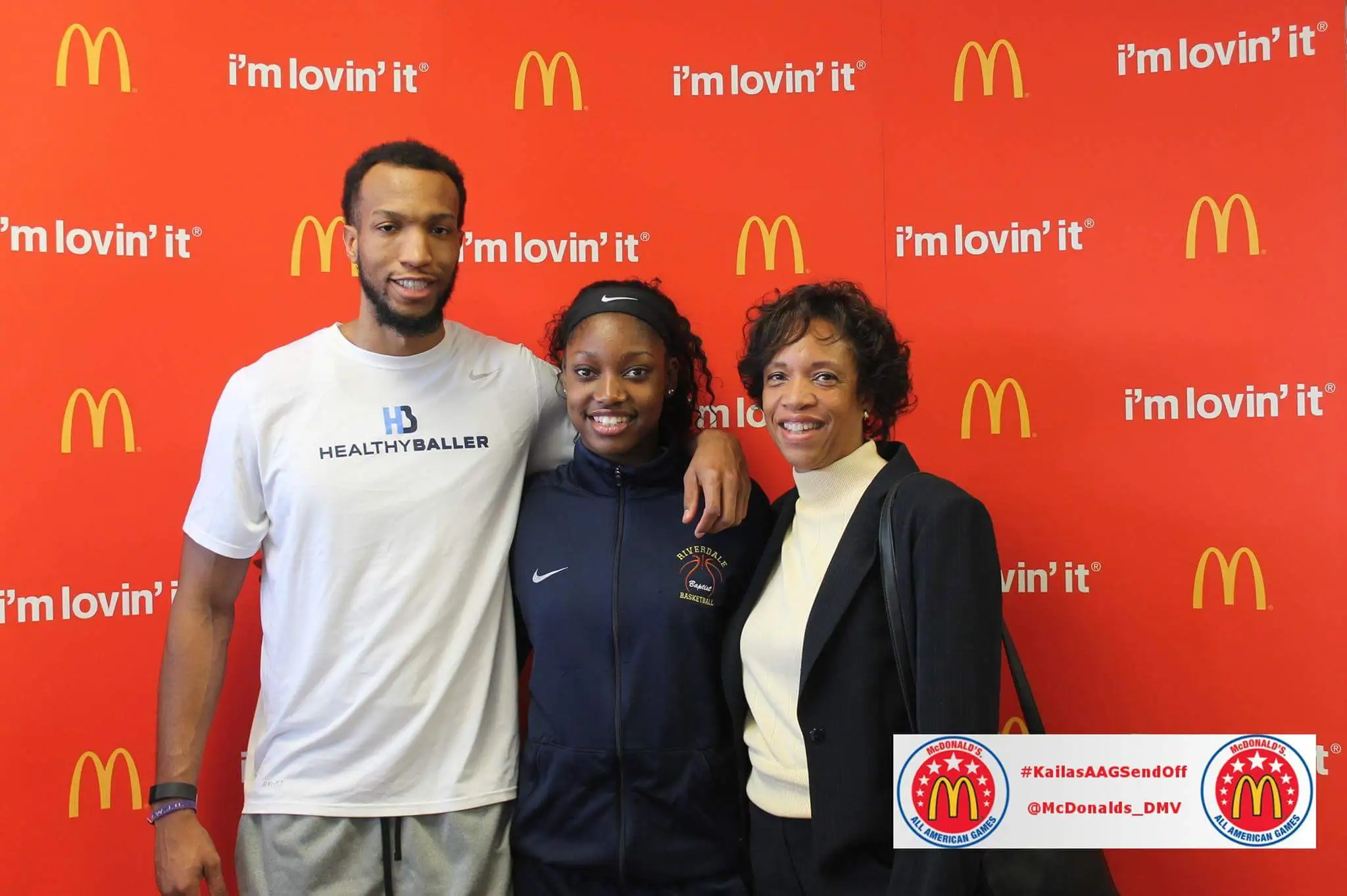 Three people posing at McDonald's event backdrop.