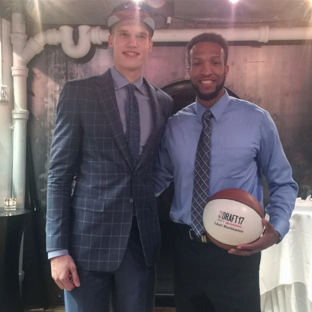 Two men in suits, holding a basketball.