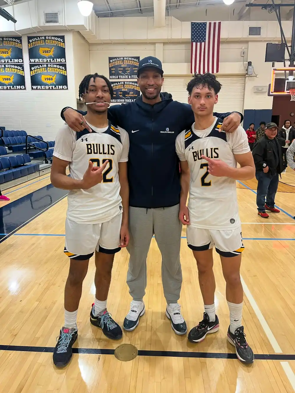 Basketball coach with two players in team uniforms.