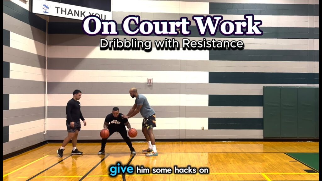 Basketball dribbling practice with resistance on court.