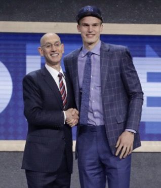 Two men in suits shaking hands on stage.