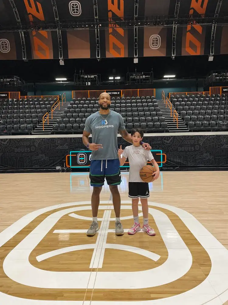 Two people posing on basketball court holding ball.