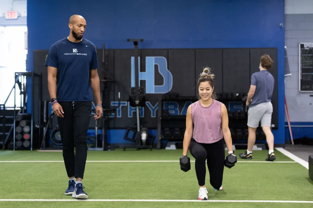 Woman doing lunges with dumbbells in gym