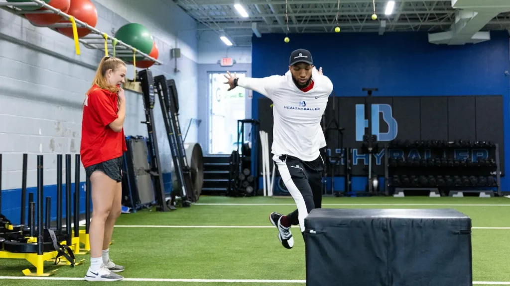 Athlete jumping over obstacle in training gym.