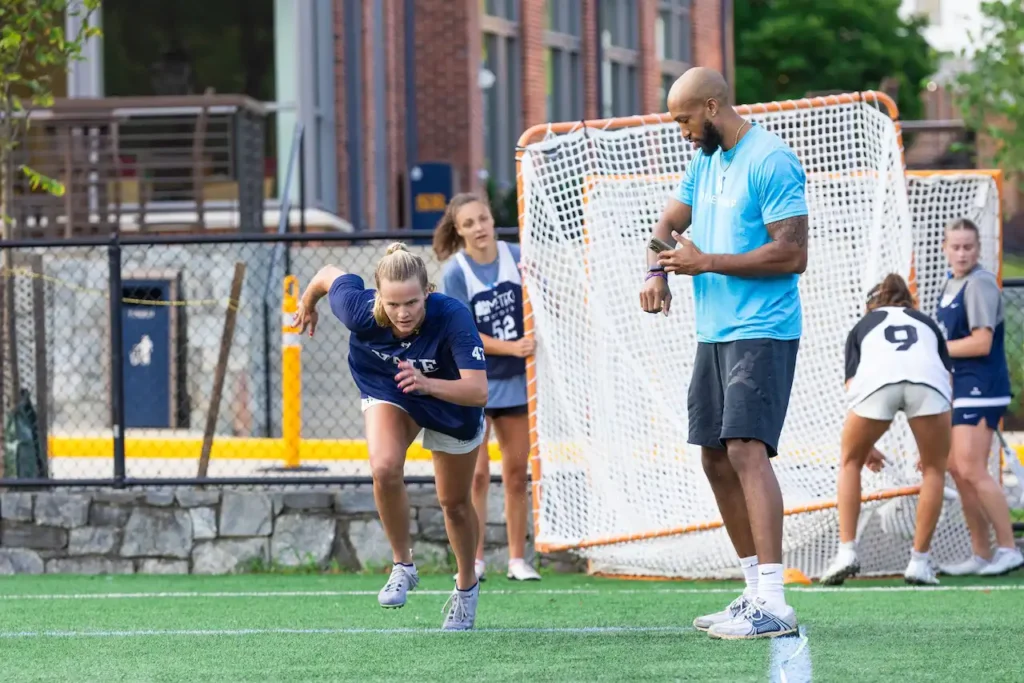 Athlete sprinting, coach timing, outdoors on field