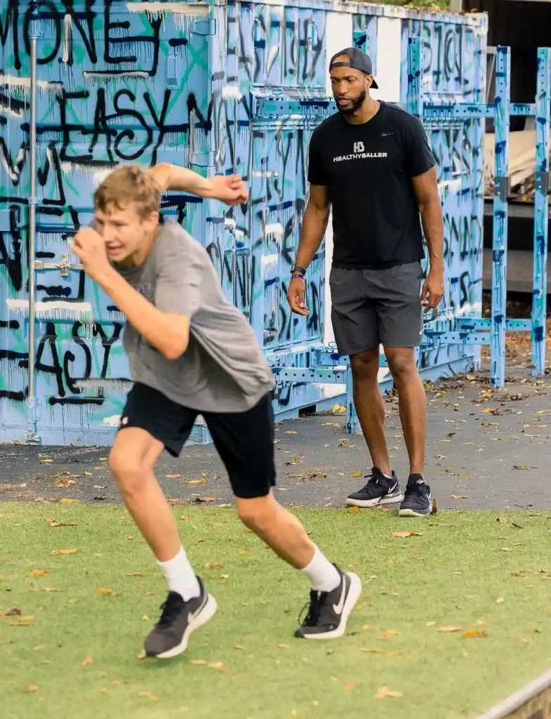 Coach training athlete on grassy field.