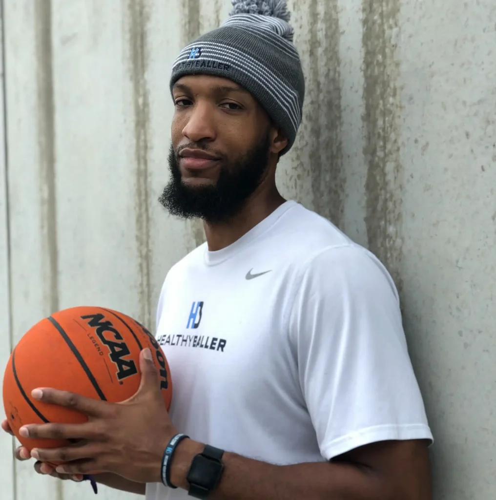 Man holding basketball against concrete wall.
