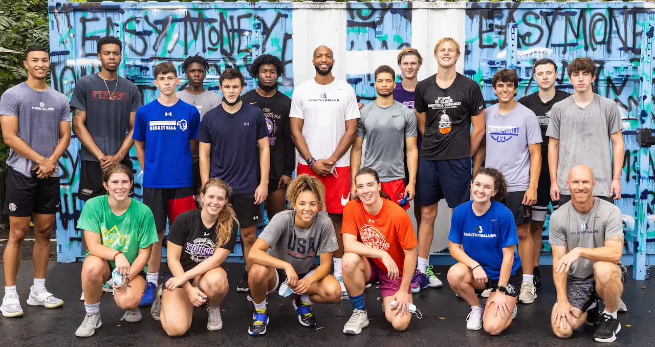 Group of athletes posing in front of graffiti wall.