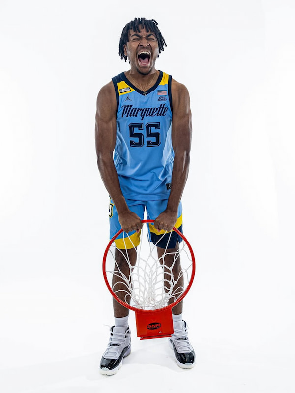 Basketball player holding rim, celebrating energetically.