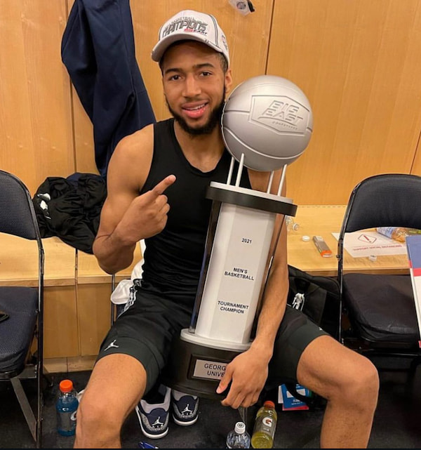 Basketball player holding trophy in locker room.