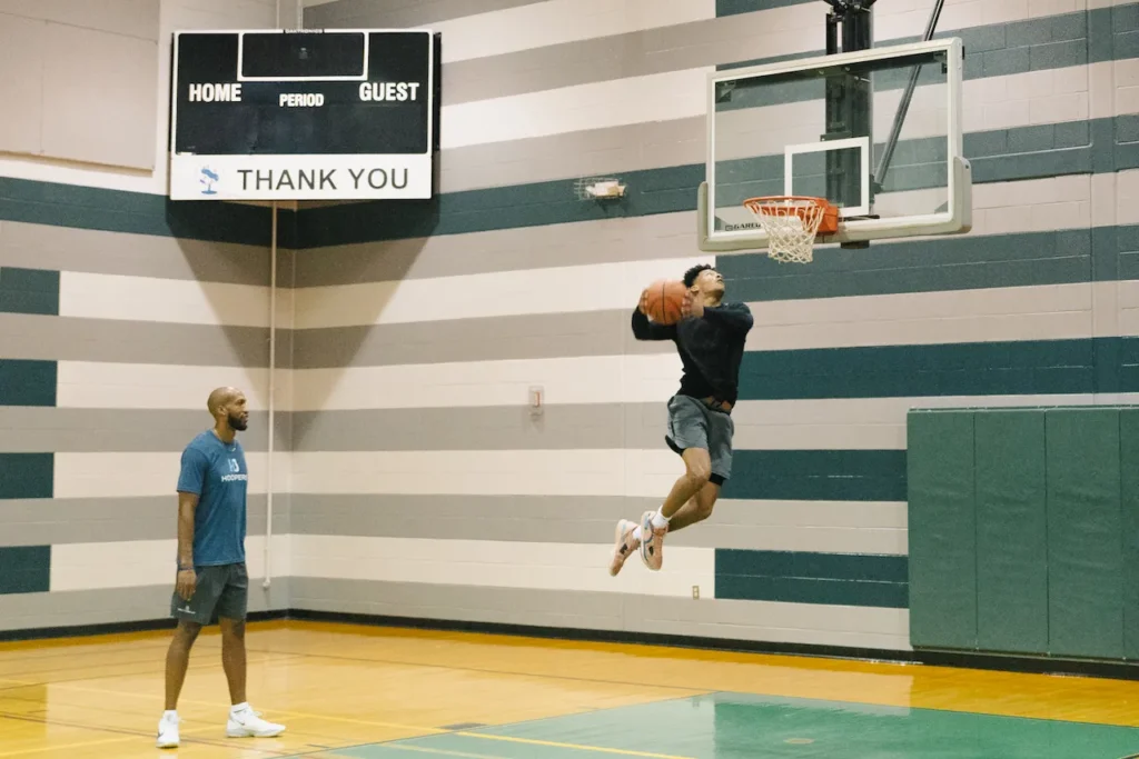 Basketball player performing a dunk in a gym.