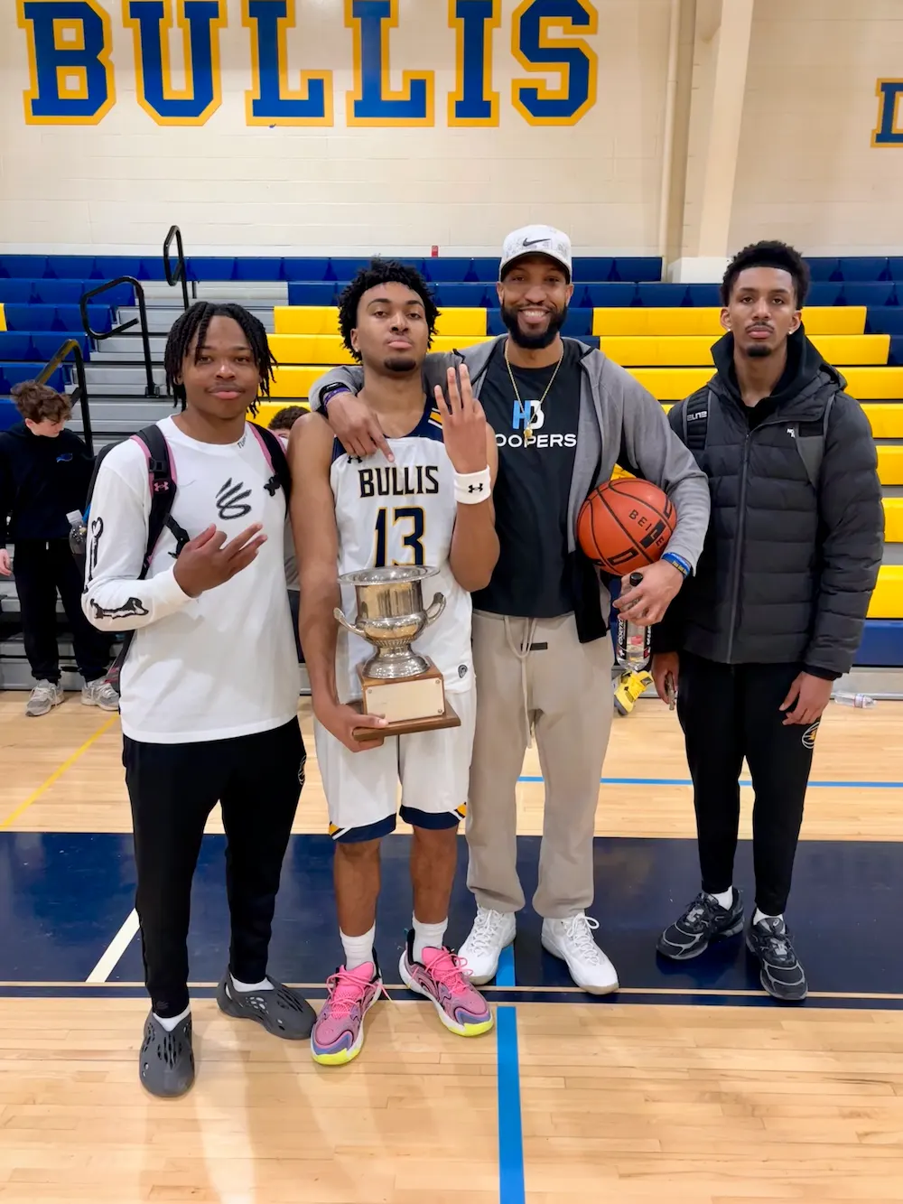 Four men celebrating with basketball trophy, Bullis team.