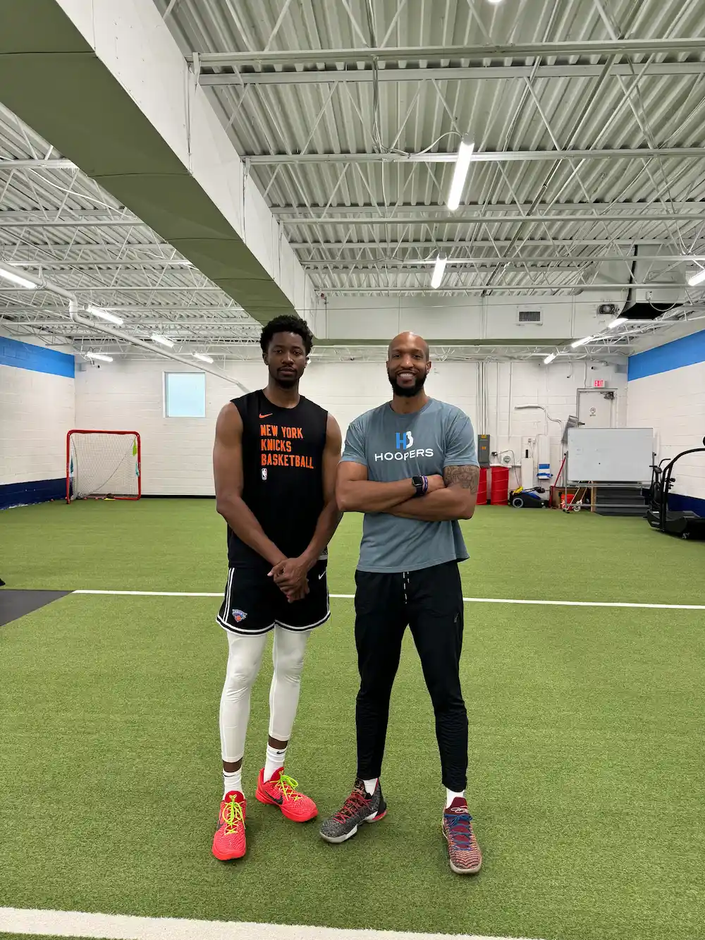 Two men posing in indoor sports facility.