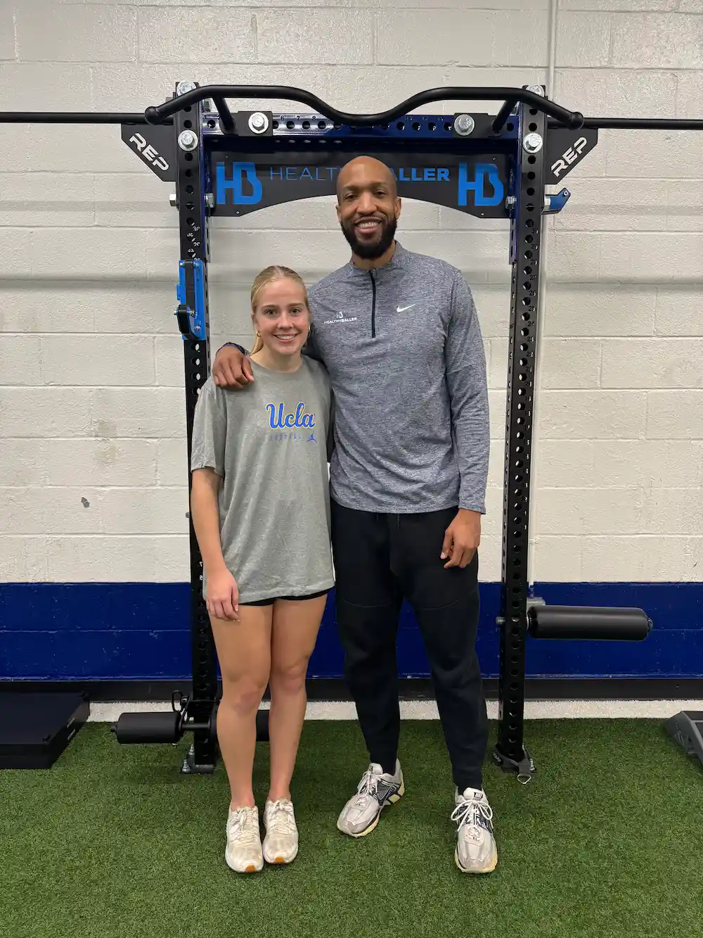 Two people in a gym, smiling together.
