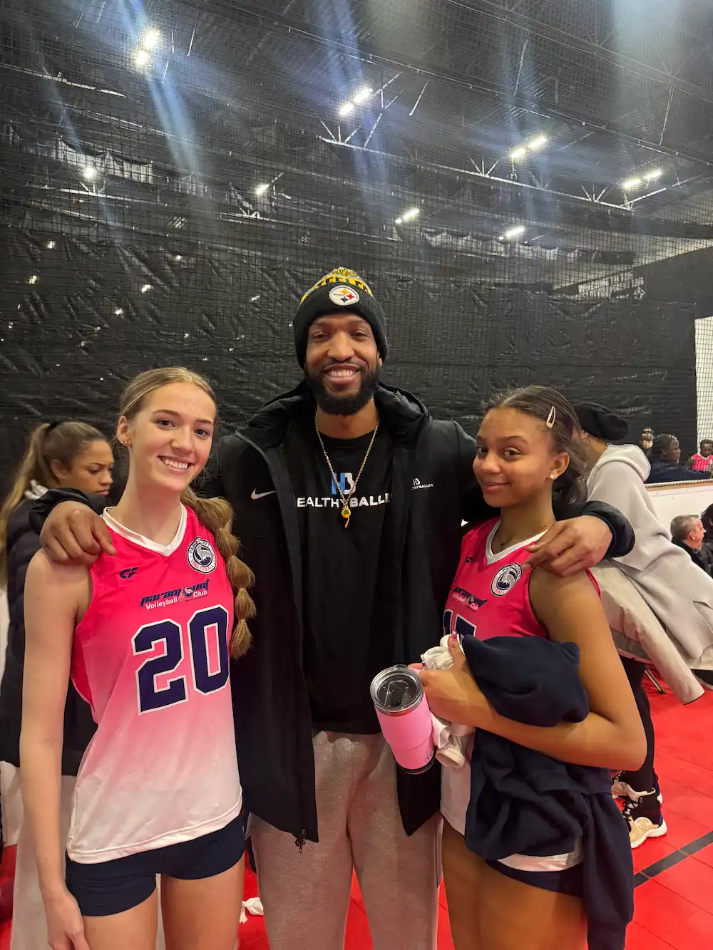 Three smiling people at a volleyball event.