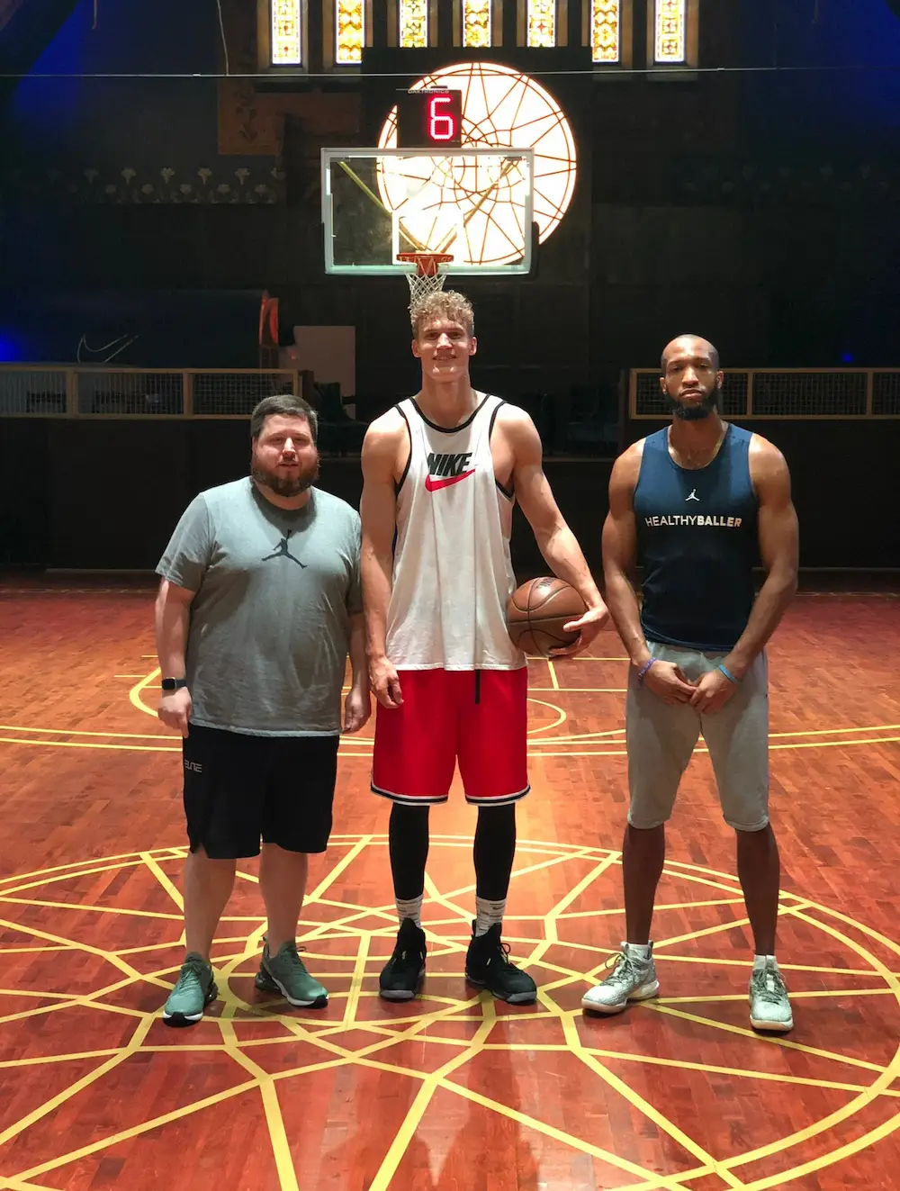 Three men on a basketball court posing together