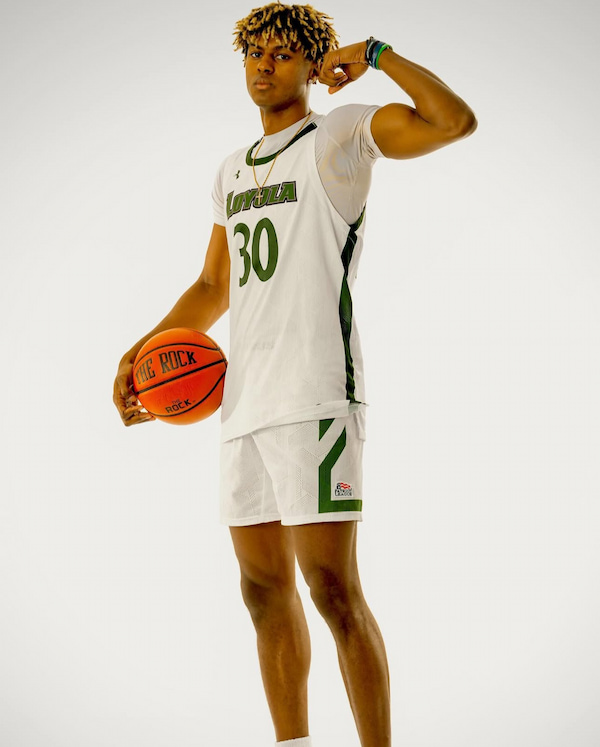 Basketball player in white uniform holding a ball.
